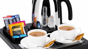 Una cafetera, dos tazas de café y una bandeja con cápsulas de café y una cuchara.