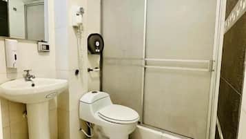 Un baño con inodoro, lavamanos y zona de ducha.