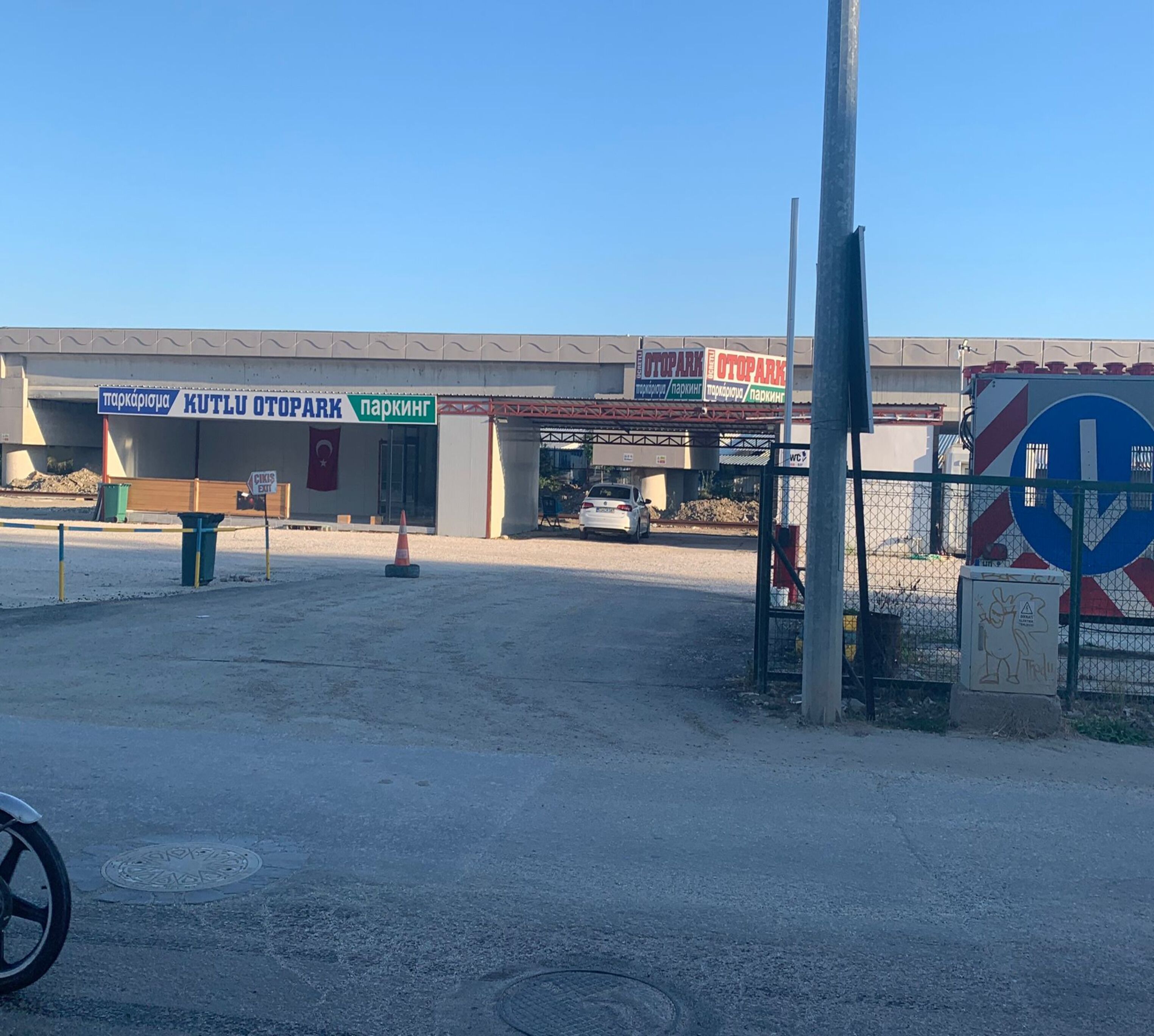 Un área de estacionamiento con un cartel que dice 'KUTLU OTOPARK' y una bandera turca.