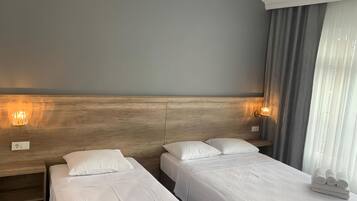 Ett hotellrum med två separata sängar, en sänggavel i trä, ett nattduksbord och en lampa.