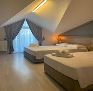 A modern hotel room with two beds, a large window with curtains, and a skylight. - Rinascente (Edirne)