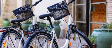 Deux vélos sont garés devant un immeuble doté de grandes fenêtres et d’une façade en briques.