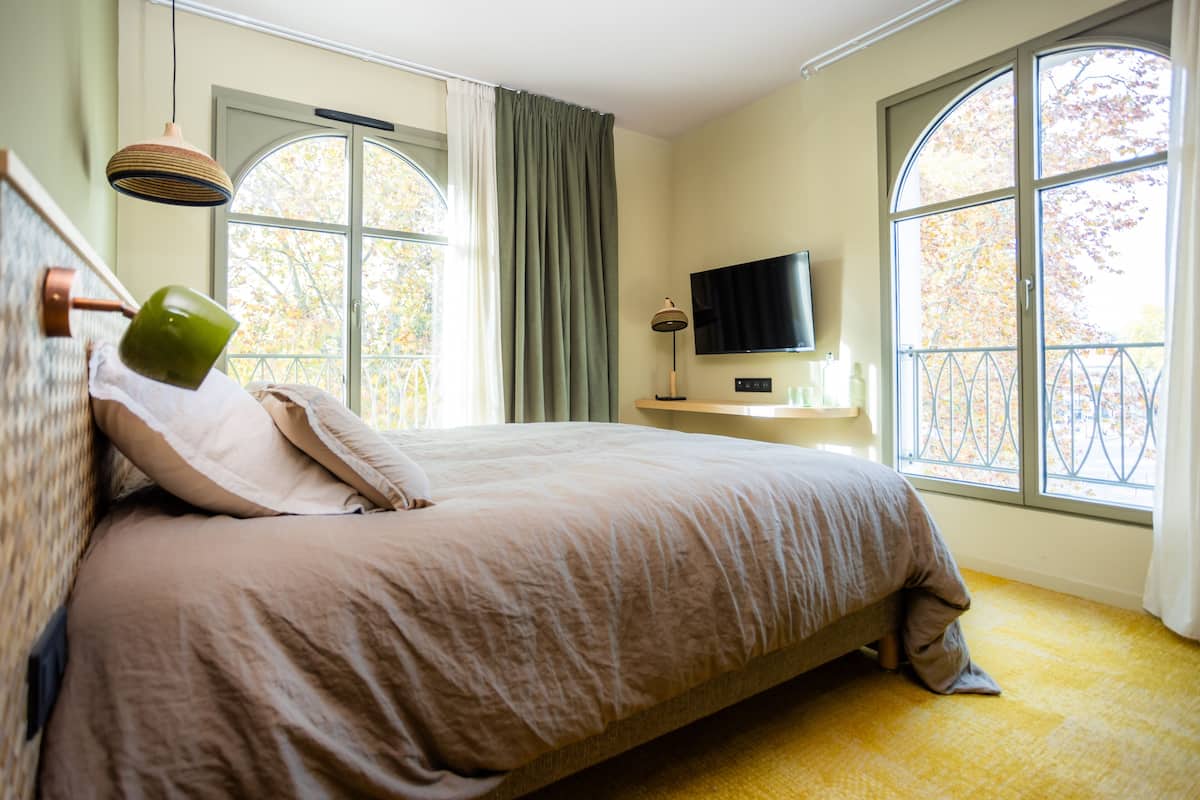 Une chambre à coucher avec un lit, une télévision et de grandes fenêtres.