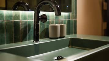 Un lavamanos de baño con una llave moderna y azulejos verdes.