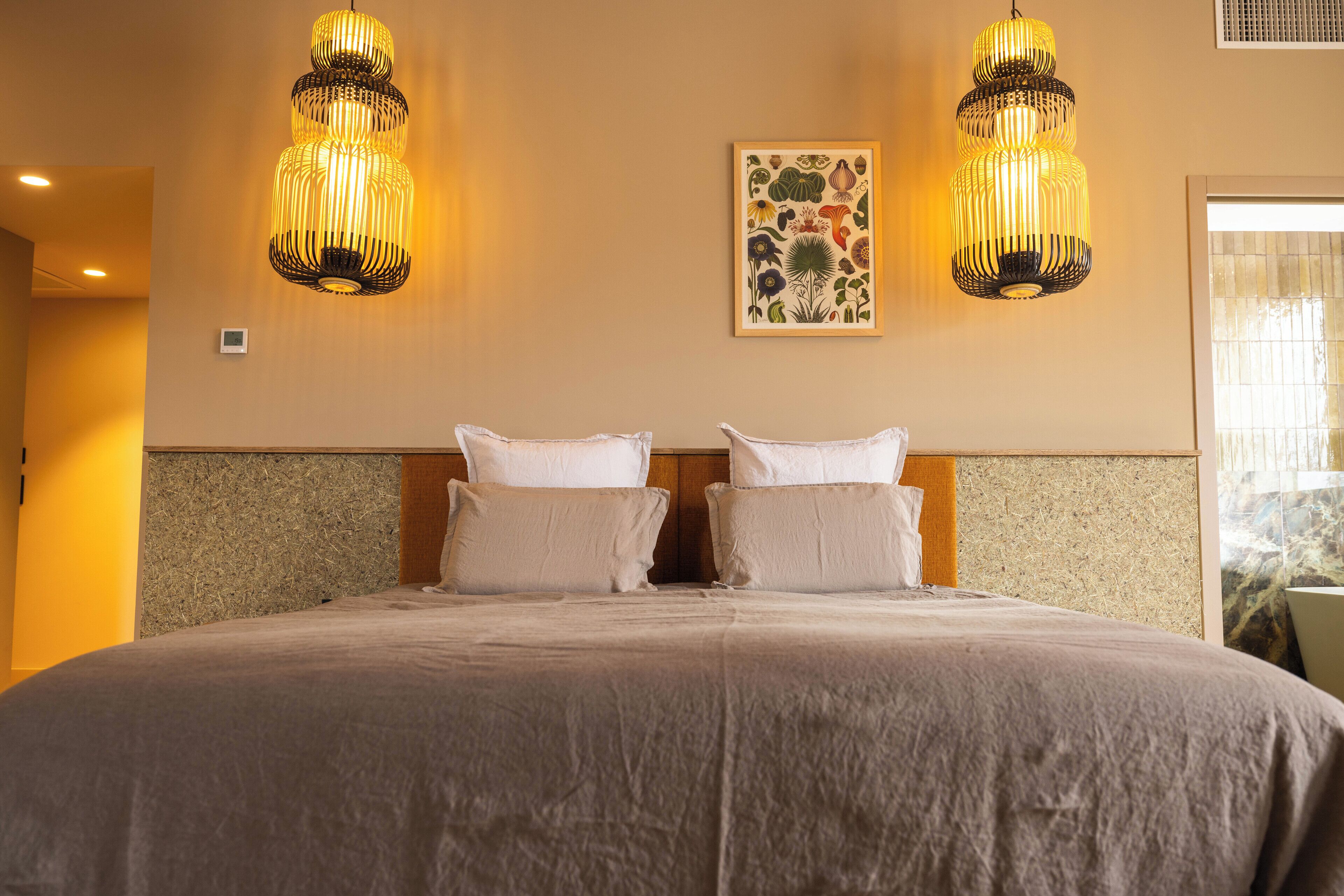 Een hotelkamer met een groot bed, twee wandlampen en een bloemkunstwerk aan de muur.