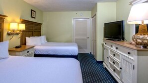 Ein Hotelzimmer mit zwei Betten, einem Fernseher, einem Schminktisch und einer Lampe.