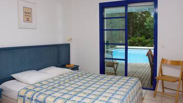 Un dormitorio con cama, mesita de noche, un cuadro enmarcado en la pared y vista a una piscina a través de una puerta de cristal.