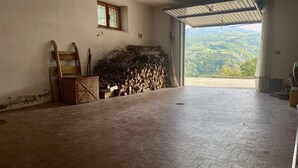 Une pièce avec un sol en briques, une fenêtre, une porte et une vue sur un paysage montagneux.