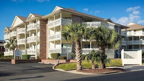 A multi-story hotel with balconies, a brick facade, and palm trees. - Seaside Splendor: Fully Remodeled 2BR Resort View (Myrtle Beach)