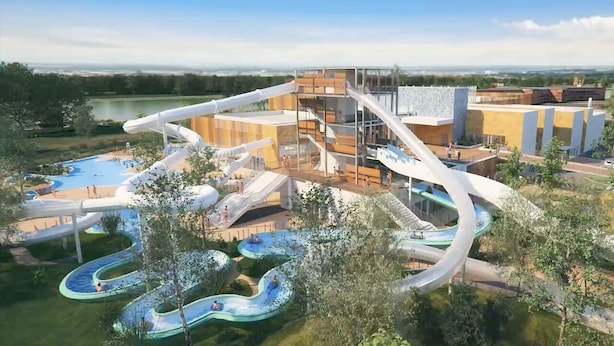 Een waterpark met meerdere glijbanen en zwembaden, omgeven door bomen en gebouwen.
