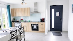 Een moderne keuken met houten kastjes, een zwarte oven en een eethoek met een tafel en stoelen.