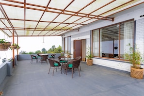 A covered patio area with wicker furniture and potted plants.