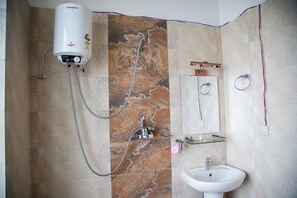 A bathroom with a wall-mounted heater, a shower with a handheld showerhead, a glass shelf with a mirror, and a sink.