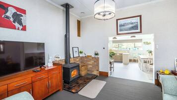 A living room with a TV, wooden cabinet, fireplace, and a dining area with chairs and a table.