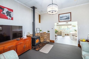 Una sala de estar con televisor, aparador de madera, chimenea y un comedor con sillas y una mesa.