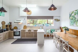 A modern kitchen with a central island, pendant lighting, and a view to the outdoors. - The Farmhouse On Church (Greytown)