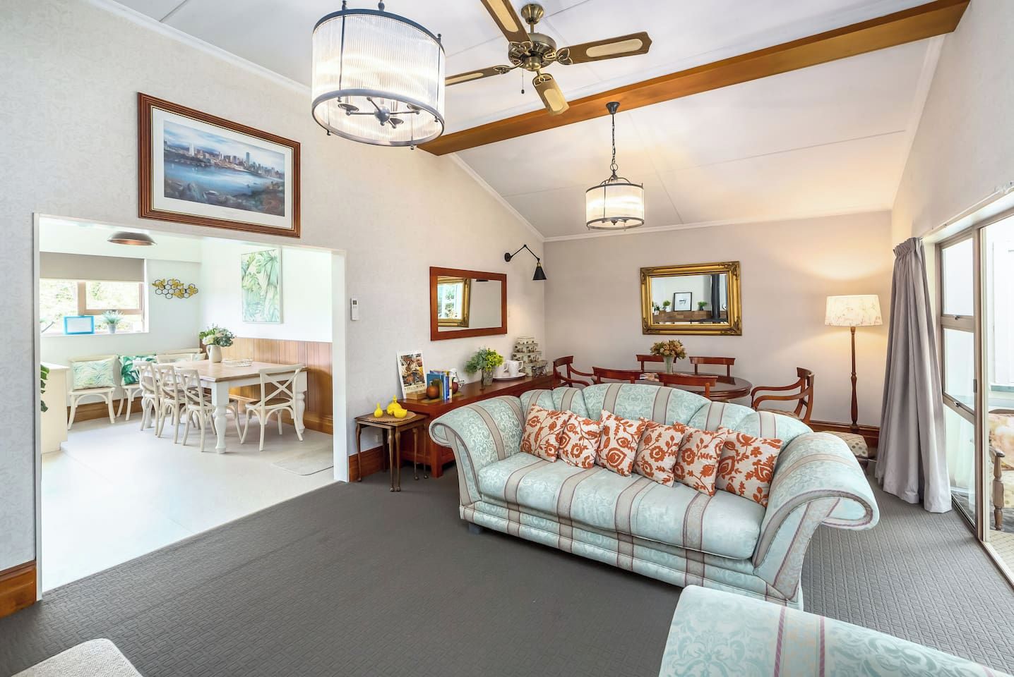 A living room with a sofa, dining table, chairs, and a ceiling fan.