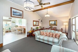 A living room with a sofa, dining table, chairs, and a ceiling fan.