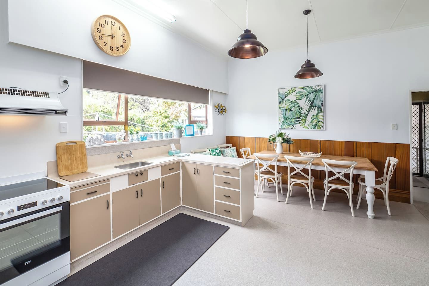 A modern kitchen with a dining area, featuring a stove, sink, cabinets, and a dining table with chairs.