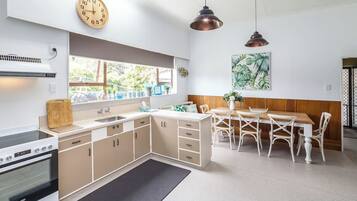 A modern kitchen with a dining area, featuring a stove, sink, cabinets, and a dining table with chairs.