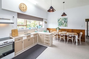 Cocina moderna con comedor, que incluye estufa, pileta, alacenas y una mesa con sillas.