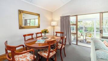 Un coin repas avec une table ronde, six chaises, un vase de fleurs et un miroir encadré accroché au mur.