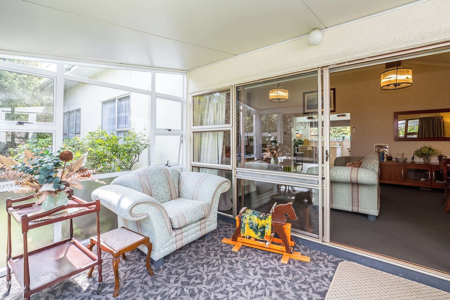 A spacious living area with a large window, a sofa, a small table, and a decorative plant.