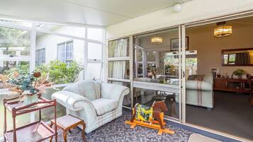 A spacious living area with a large window, a sofa, a small table, and a decorative plant.