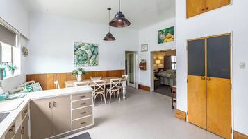 A modern kitchen with a dining area, wooden cabinets, and pendant lighting.