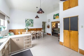 A modern kitchen with a dining area, wooden cabinets, and pendant lighting.