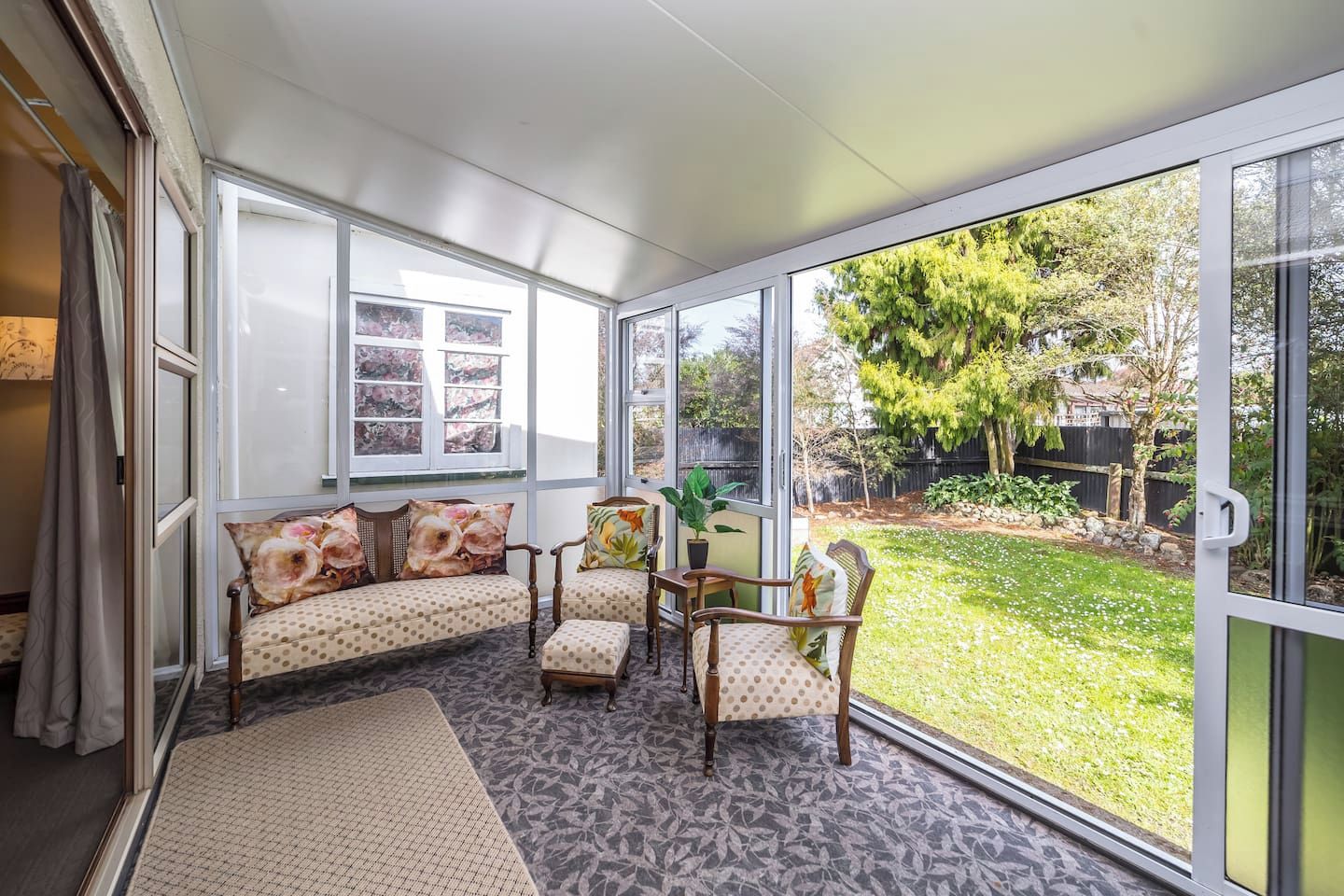 A sunroom with a large glass door, a sofa set, two chairs, and a small table.