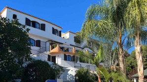 A white building with balconies and a pool area with lounge chairs. - La Piña Verde (Estepona)