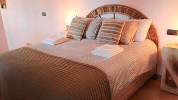 A neatly made bed with a striped headboard, a bedside table with a lamp, and a wall-mounted light fixture.