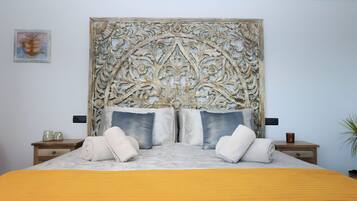 Un dormitorio con un cabecero grande y ornamentado, una cama con colcha amarilla y dos mesitas de noche con lámparas.