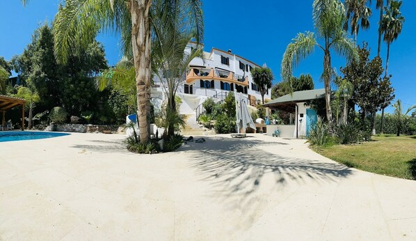 Ein Resort mit Swimmingpool, Palmen und einem großen Gebäude mit mehreren Balkonen.
