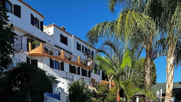 A pool area with lounge chairs and a white building with balconies. - La Piña Verde (Estepona)
