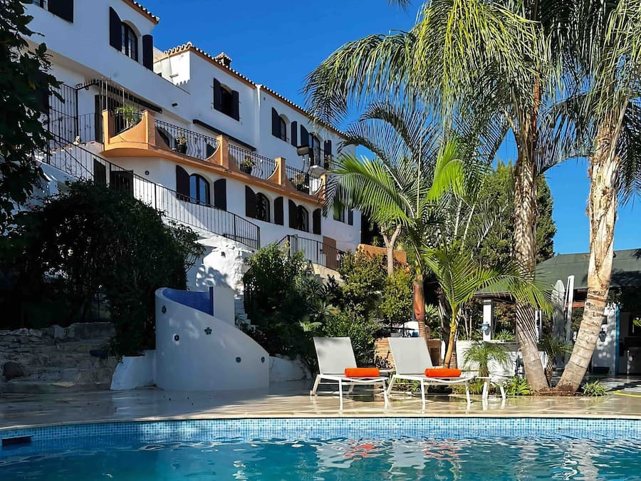 Una piscina al aire libre, sombrillas, tumbonas