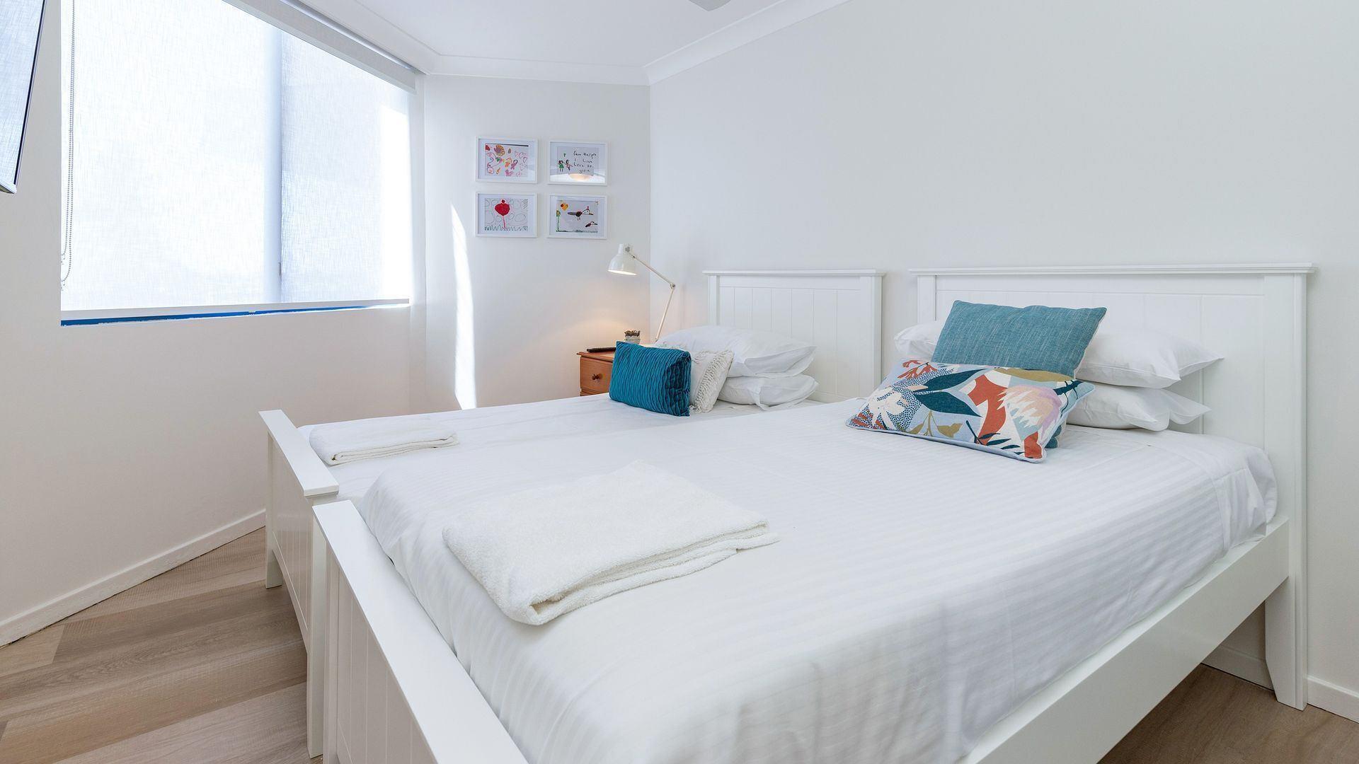 A bedroom with a large bed, white bedding, and a window with blinds.