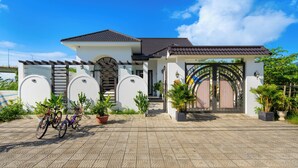 Una casa moderna con techo de tejas, entrada portón y plantas en macetas.