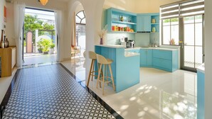 Una cocina moderna con armarios azules, una isla central y una zona de comedor con taburetes de bar.