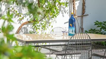 A patio with a metal table and chairs, a blue bottle, and a wall with climbing plants.