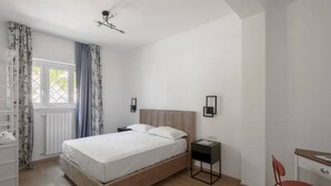 Une chambre à coucher avec un lit, des tables de chevet, un bureau et une chaise.