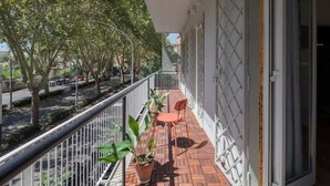 Un balcon avec un sol en briques, deux chaises et des plantes en pot.