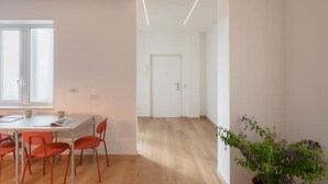 Une pièce moderne et minimaliste, dotée d’un plancher en bois, d’une porte blanche et d’un coin repas avec une table et des chaises.