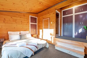 Ein Schlafzimmer einer Holzhütte mit einem Bett, Nachttischen und einem großen Kleiderschrank.