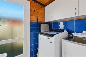 Eine Küche mit Waschmaschine, Schränken und einem Fenster mit Blick.