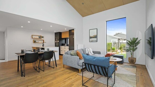 A modern living space with a dining area, a sofa, and a TV. - The Sanctuary - Modern, Spa Pool, Sleeps 4 (Rotorua)