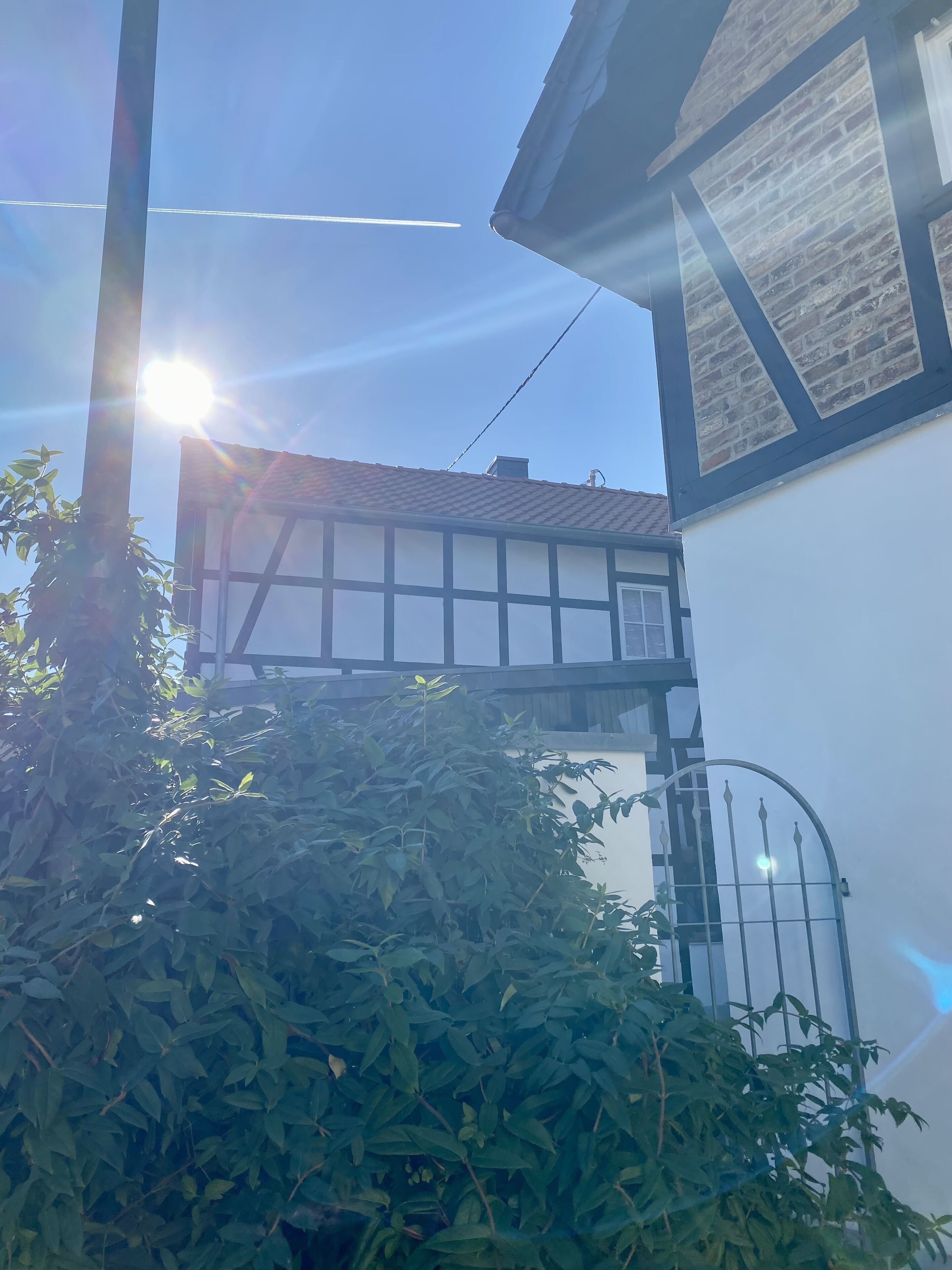 Une maison traditionnelle à colombages, avec une fenêtre de grenier visible et un portail en métal.