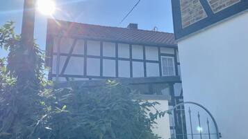 Une maison traditionnelle à colombages, avec une fenêtre de grenier visible et un portail en métal.