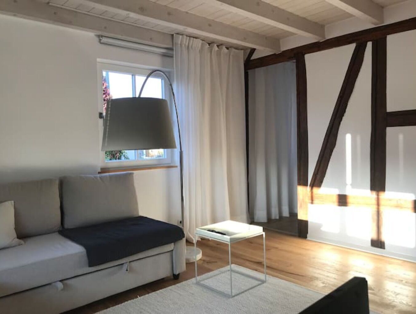 A modern living room with a sofa, a small table, and a window with curtains.